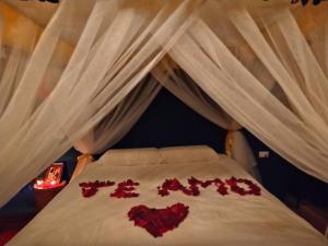 a bed with hearts written on the bedsheets at Cabaña Macareo in Tuluá