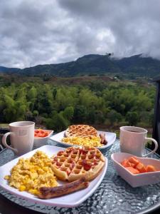 a table with three plates of breakfast food on it at Cabaña Macareo in Tuluá