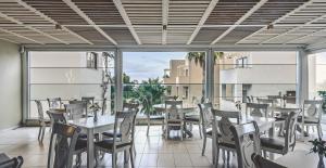 a restaurant with tables and chairs and a large window at Althea Village - Family Hotel in Kato Daratso