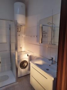 a white bathroom with a washing machine and a sink at Nika's Sea View Oasis in Seget