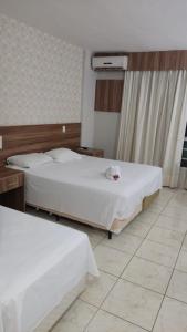 a hotel room with two beds and a window at Ecologic Ville Resort Apto há 900 mt do centro de Caldas Novas in Caldas Novas