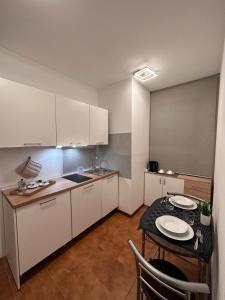 a kitchen with a table and a small kitchen with white cabinets at ROMA HOME in Udine