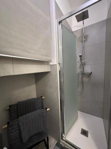 una ducha con una puerta de cristal junto a una silla en ROMA HOME, en Udine