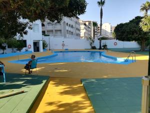 a person sitting in a chair by a swimming pool at Primera línea de Playa in Almuñécar