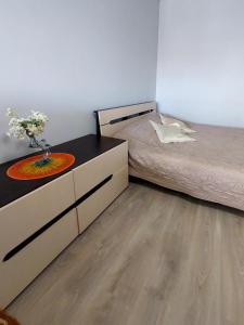 a bedroom with a bed and a dresser with a vase of flowers at Дво і одно кімнатні апартаменти новобуд рн авторинку трц Адреналін сіті in Lutsk