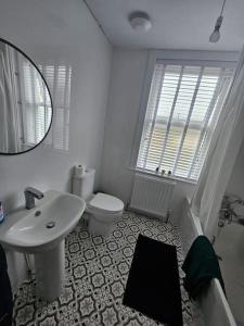 een badkamer met een wastafel, een toilet en een spiegel bij HollyJess Hoose in Stranraer