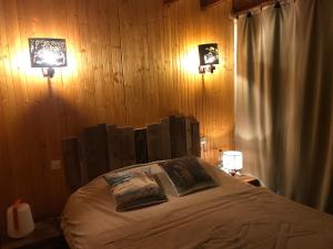 sypialnia z łóżkiem z drewnianymi ścianami i dwoma światłami w obiekcie Chalet dans clairiere w mieście Bolquere Pyrenees 2000