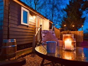 a candle on a table in front of a house at Whiskers and Woods Shepherd Hut in Denham