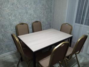 een tafel en stoelen in een kamer met behang bij Уютная 3-х комнатная квартира in Oral