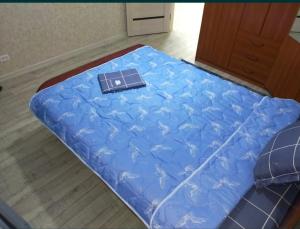 een blauw bed met een boek erop bij Уютная 3-х комнатная квартира in Oral