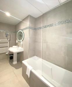 a bathroom with a bath tub and a sink at Hôtel Le Royal Promenade des Anglais in Nice