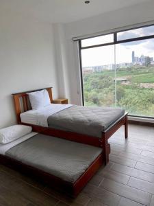 a bedroom with two beds and a large window at Departamento en lomas de angelopolis, Isla blanca in Lomas de Angelopolis