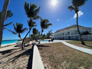 - un bâtiment sur la plage avec des palmiers dans l'établissement Exuma Palms Resort, à Hermitage