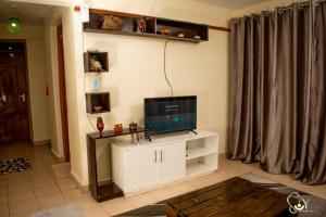 uma sala de estar com televisão num armário branco em The Unit em Nyeri