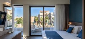 a hotel room with a bed and a large window at Althea Village - Family Hotel in Kato Daratso