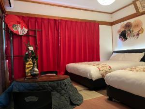 Yokkaichi City Guest House في يوكايتشي: غرفة فندقية بسريرين وستائر حمراء
