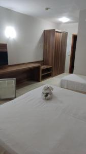 a stuffed animal sitting on a bed in a bedroom at Ecologic Ville Resort Apto há 900 mt do centro de Caldas Novas in Caldas Novas