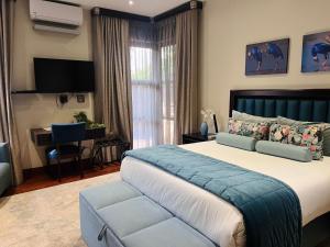a bedroom with a bed and a desk and a television at One O Eight Boutique Hotel in Benoni +25 photos