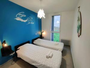 2 camas en una habitación con una pared azul en Appartement T3 avec piscine, climatisation, wifi et garage en Collioure