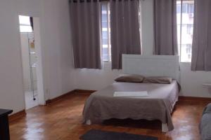 a bedroom with a bed and two windows at Apartamento 74 Consolação Centro in Sao Paulo