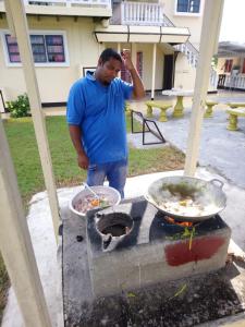 un hombre cocinando comida en una parrilla al aire libre en Huize Beekhuizen, en Paramaribo