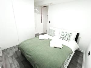 a white bedroom with a green bed with pillows at Studio with Bathroom and Kitchen 20 minutes from Central London in London