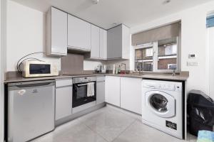 a kitchen with white cabinets and a washer and dryer at Garden Studio flat in Hendon in Hendon