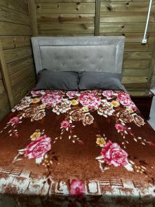 ein Bett mit einer Decke mit Blumen drauf in der Unterkunft Casa confortável 2 quartos Itacolomi Balneário Picarras ,Beto Carrero in Piçarras