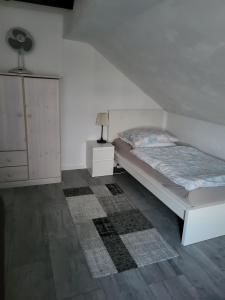 a white bedroom with a bed and a dresser at Ferienwohnung in Hövelhof