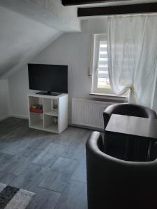 a living room with a flat screen tv and chairs at Appartement Ferienwohnung in Hövelhof