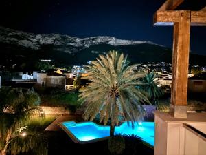 a palm tree sitting next to a swimming pool at night at Hoteltype Penthouse 2 Beds, Parking, WIFI & pool Stunning Views in Denia