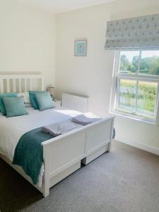 a white bedroom with a bed and a window at Steam Train Cottage - Lake District Hideaway in Newby Bridge