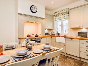 a kitchen with a table with chairs and a clock on the wall at Steam Train Cottage - Lake District Hideaway in Newby Bridge