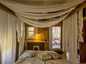 ein Schlafzimmer mit einem Himmelbett und Kissen in der Unterkunft la Casa dei Gatti a Seccheto, una chicca in Seccheto