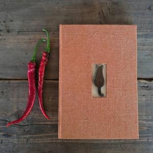 zwei rote Gemüse liegen auf einem Buch in der Unterkunft la Casa dei Gatti a Seccheto, una chicca in Seccheto