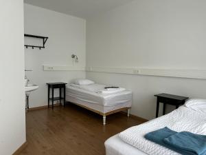 Habitación blanca con 2 camas y lavamanos en Kanslarinn Hostel en Hella