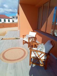 dwa krzesła siedzące na ganku z oknem w obiekcie Praia Encantada w mieście Porto Santo