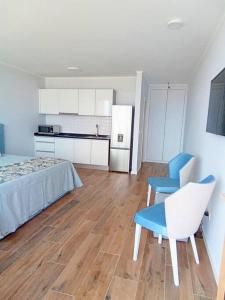 a bedroom with a bed and a chair and a kitchen at Praia Encantada in Porto Santo