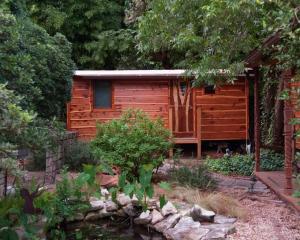 una cabaña de madera con un estanque frente a ella en The Treecycle, en Austin