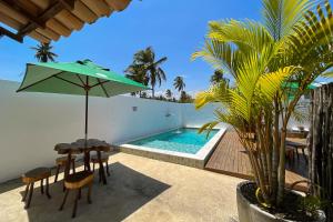 a patio with a pool and a table with an umbrella at Villa Nahum ER Hospedagens in São Miguel dos Milagres