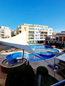 a large pool with a white umbrella next to a building at Pool View Apartment, Sunny Beach Resort in Sunny Beach