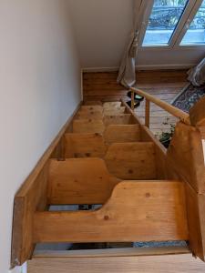 ein Dachgeschoss mit Holztreppe in einem Zimmer mit Fenster in der Unterkunft Chambre bohème au calme in Montrouge