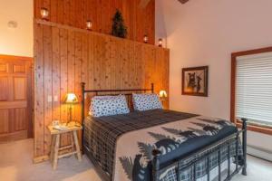1 dormitorio con 1 cama con pared de madera en Lake Superior Cabin with Fireplace Snowmobile Trails, en Paradise