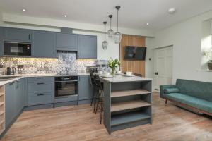 a kitchen with blue cabinets and a blue couch at Gibson Cottage, Penrith, The Lake District in Penrith