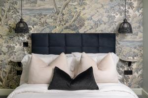 Una cama blanca con almohadas negras en un dormitorio en Gibson Cottage en Penrith