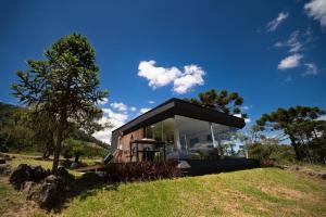 a small house on top of a grassy hill at The Altitude Cabana 1374-Black in Urubici