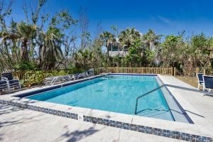 a swimming pool with chairs and a fence and trees at Sealoft Village #105 - Come stay on Sanibel! in Sanibel