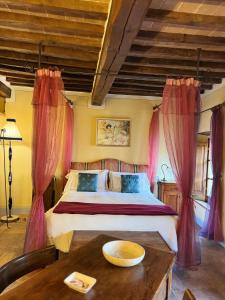 a bedroom with a bed with pink curtains and a table at Pienzalettings "Suites" in Pienza
