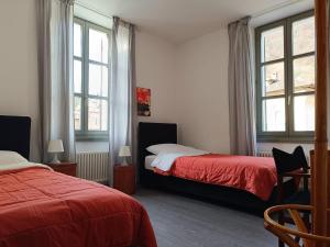 a bedroom with two beds and two windows at Locanda La Pignatta in Arogno
