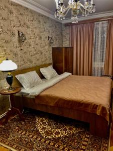 1 dormitorio con cama, mesa y lámpara de araña en Travel-fun, en Tiflis